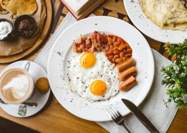 top view english breakfast fried egg beans sausages bacon and cup of coffee on the table