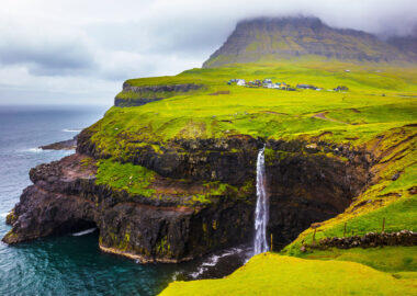 Dramatic waterfall on Faroe Islands and the village Gasadalur in the background. Rainy day in july.